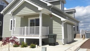 A two-story house with a covered porch and a small front yard. - Direct Bay Front,  Panoramic Bay and Sunset Views, Boat Dock/Slip, Large porch on the wide open bay! (Ocean City)