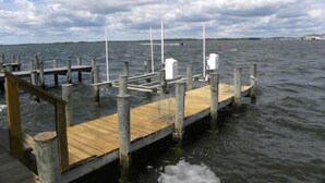 A wooden pier extending into a body of water with a clear sky and clouds above. - Direct Bay Front,  Panoramic Bay and Sunset Views, Boat Dock/Slip, Large porch on the wide open bay! (Ocean City)