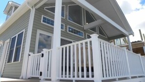 A two-story house with a covered porch and a white railing. - Direct Bay Front,  Panoramic Bay and Sunset Views, Boat Dock/Slip, Large porch on the wide open bay! (Ocean City)