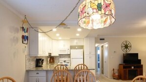 A dining area with a table, chairs, and a chandelier. - Ocean Block Condo, porch, 1st floor, steps to beach, updated, full kitchen, lg dining table, wifi! (Ocean City)