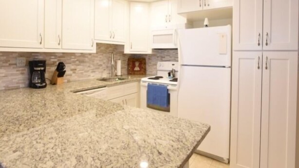 A kitchen with white cabinets, a granite countertop, a coffee maker, and a refrigerator. - Ocean Block Condo, porch, 1st floor, steps to beach, updated, full kitchen, lg dining table, wifi! (Ocean City)