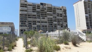 Ein Strandhotel mit einem Sandweg, der zu einem weißen Zaun und einer Treppe führt.