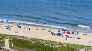 Ein Strand mit Menschen, Sonnenschirmen und blauem Himmel.