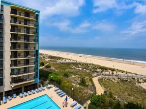 Um hotel com piscina, vista para a praia e um edifício com várias varandas.