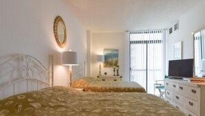 A bedroom with two beds, a television, a dresser, and a window with blinds. - Ocean Front Building w/ side views of Ocean and Beach, lifeguarded pool, Game Room, Gym, Tennis (Ocean City)