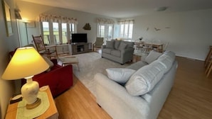 A spacious living room with a sofa, a TV, and a dining area with chairs. - Montego Bay Community BAY VIEW 4 BR 2 Bath w/ screened porch! 2 large community pools & tennis (Ocean City)