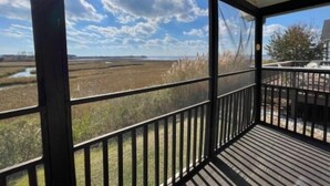 A covered porch with a view of a marshy landscape and a clear sky. - Montego Bay Community BAY VIEW 4 BR 2 Bath w/ screened porch! 2 large community pools & tennis (Ocean City)