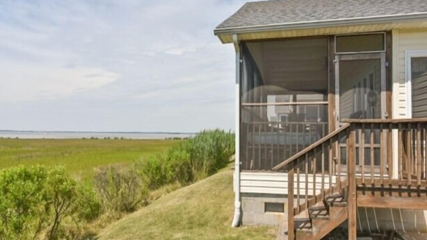 A house with a screened porch, a wooden deck, and a view of the water. - Montego Bay Community BAY VIEW 4 BR 2 Bath w/ screened porch! 2 large community pools & tennis (Ocean City)