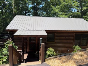 Eine Holzhütte mit Metalldach, einer Veranda und einer Schotterzufahrt.