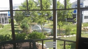 Una habitación con un amplio ventanal que da a un jardín con estanque, sillas y una pequeña mesa.