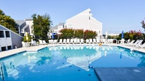 Una piscina con sillas de descanso y un edificio al fondo.