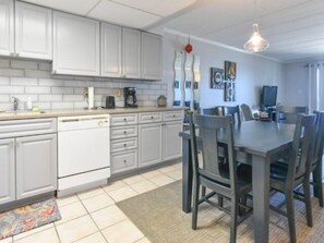 A modern kitchen with white cabinets, a dining table with chairs, and a coffee maker.