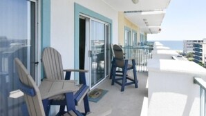 A balcony with two Adirondack chairs, a glass door, and a view of the ocean. - Ocean Block,  porch, jacuzzi tub, indoor pool, sauna, gym! Steps from the beach! (Ocean City)