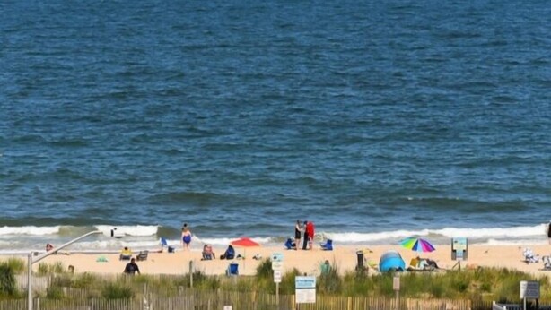 A beach with people, umbrellas, and a fence. - Ocean Block,  porch, jacuzzi tub, indoor pool, sauna, gym! Steps from the beach! (Ocean City)