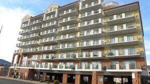 Hotel de diverses plantes amb balcons a cada planta, entrada a nivell del sòl i una zona d'aparcament al davant.