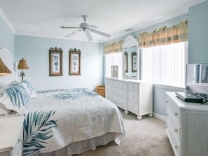 Cozy retreat with a large bed, dresser, and television.