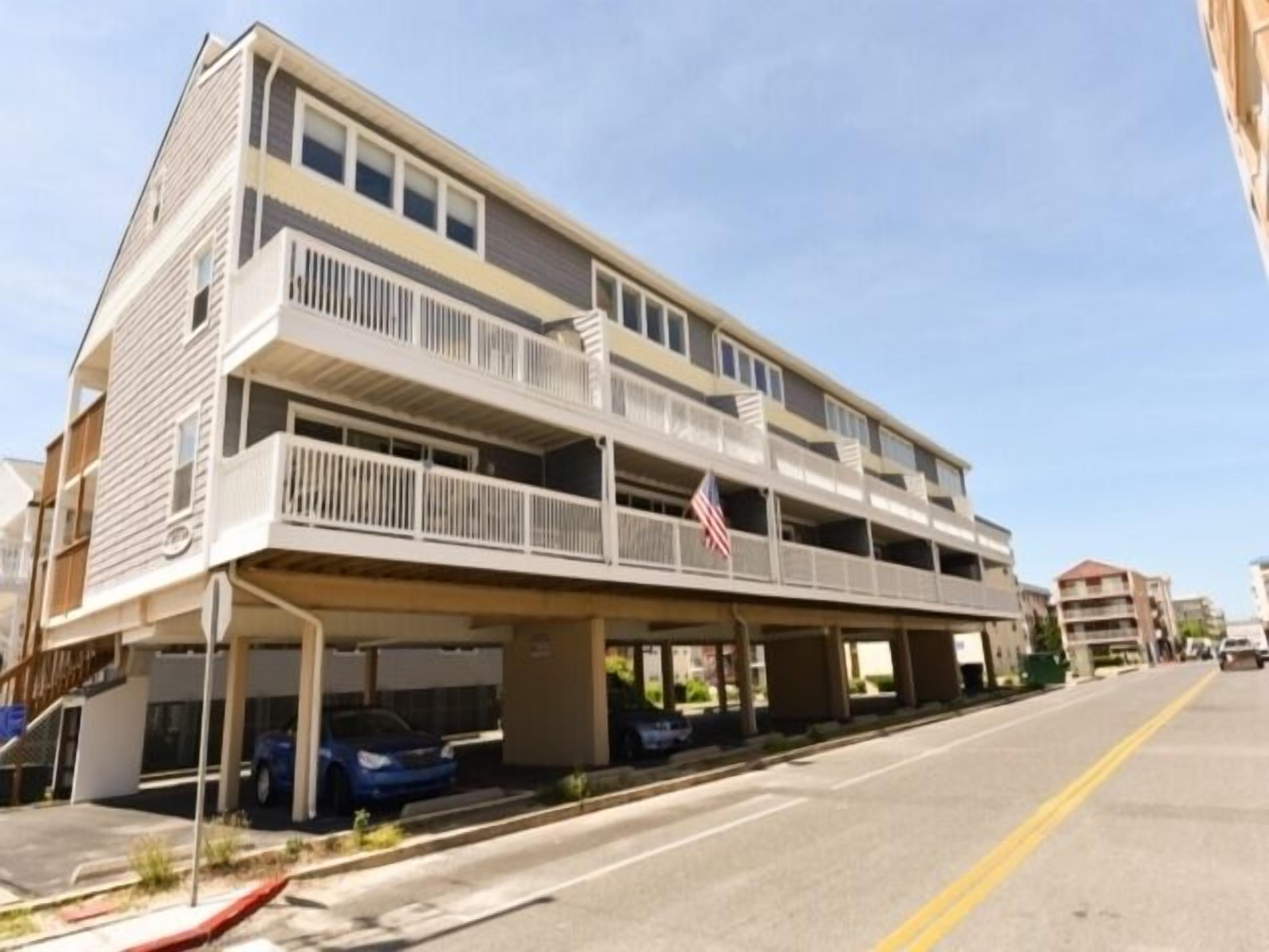 A multi-story building with a flat roof and a covered parking area.
