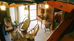 Una stanza accogliente con soffitto in legno, una sedia di legno, un tavolino e una lampada.