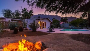 A backyard with a fire pit, a swimming pool, and a house with large windows. - Stylish Mid Century Krisel Oasis -New pool deck, Salt Water Pool, Firepit, BBQ (Palm Springs)