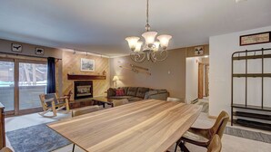 A spacious living room with a wooden dining table, leather chairs, a fireplace, and a chandelier. - Sundowner II 203 (Breckenridge)