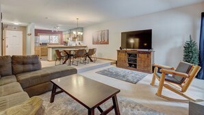 A living room with a sofa, coffee table, and a wooden rocking chair. There is a TV mounted on the wall and a small Christmas tree. - Sundowner II 203 (Breckenridge)