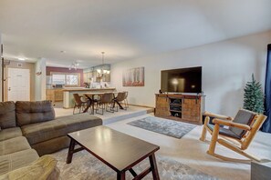A living room with a sofa, coffee table, and a wooden rocking chair. There is a TV mounted on the wall and a small Christmas tree. - Sundowner II 203 (Breckenridge)