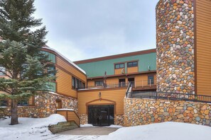 Ein Gebäude mit einer Stein-Fassade, Holzverkleidung und einem mit Schnee bedeckten Untergrund.