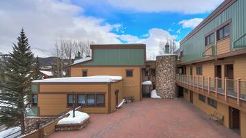 A building with a stone pillar, a covered walkway, and a snow-covered ground.