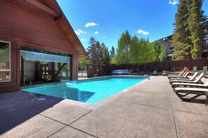 A swimming pool with lounge chairs and a wooden building with a covered entrance. - Sundowner II 203 (Breckenridge)