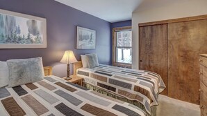 A bedroom with two beds, a wooden wardrobe, and a window with a view of trees. - Sundowner II 203 (Breckenridge)