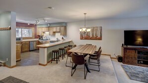 A spacious kitchen with a central island, wooden cabinets, and a dining area with a large table and chairs. - Sundowner II 203 (Breckenridge)