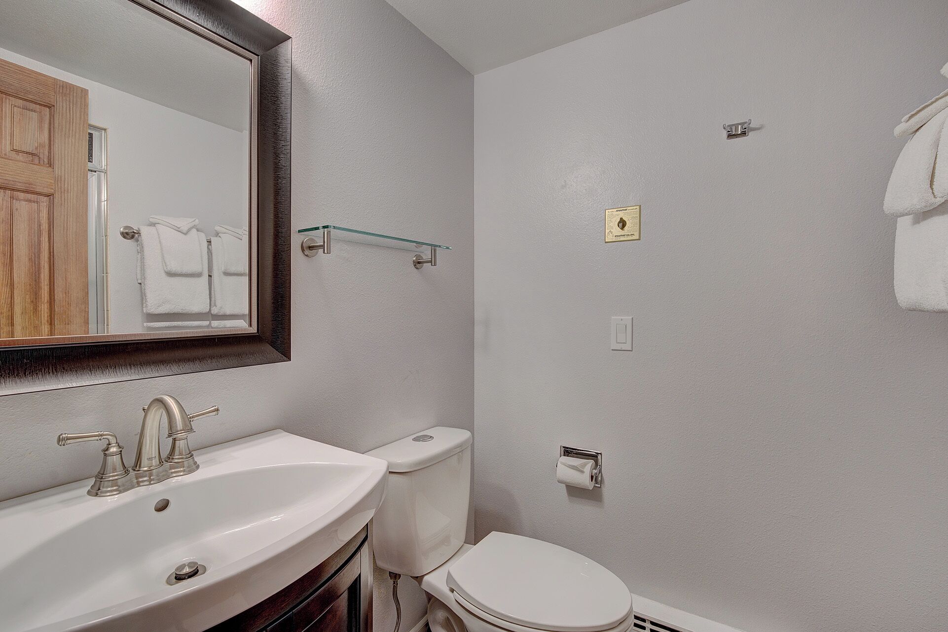 A bathroom with a sink, mirror, toilet, and towel rack.