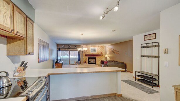 A kitchen with wooden cabinets, a central island, and a dining area with a fireplace. - Sundowner II 203 (Breckenridge)