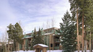 A lodge with multiple buildings, surrounded by tall evergreen trees and a snowy landscape. - Sundowner II 203 (Breckenridge)