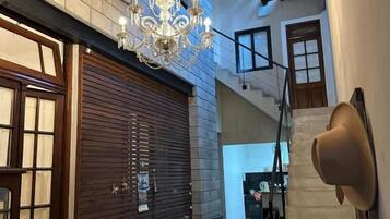 A hallway with a chandelier, wooden benches, a staircase, and a door.