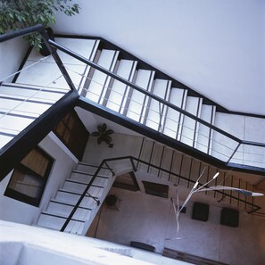 A multi-level interior with a staircase, a plant, and a wall-mounted light fixture. - Hostel Carlos Gardel (Buenos Aires)
