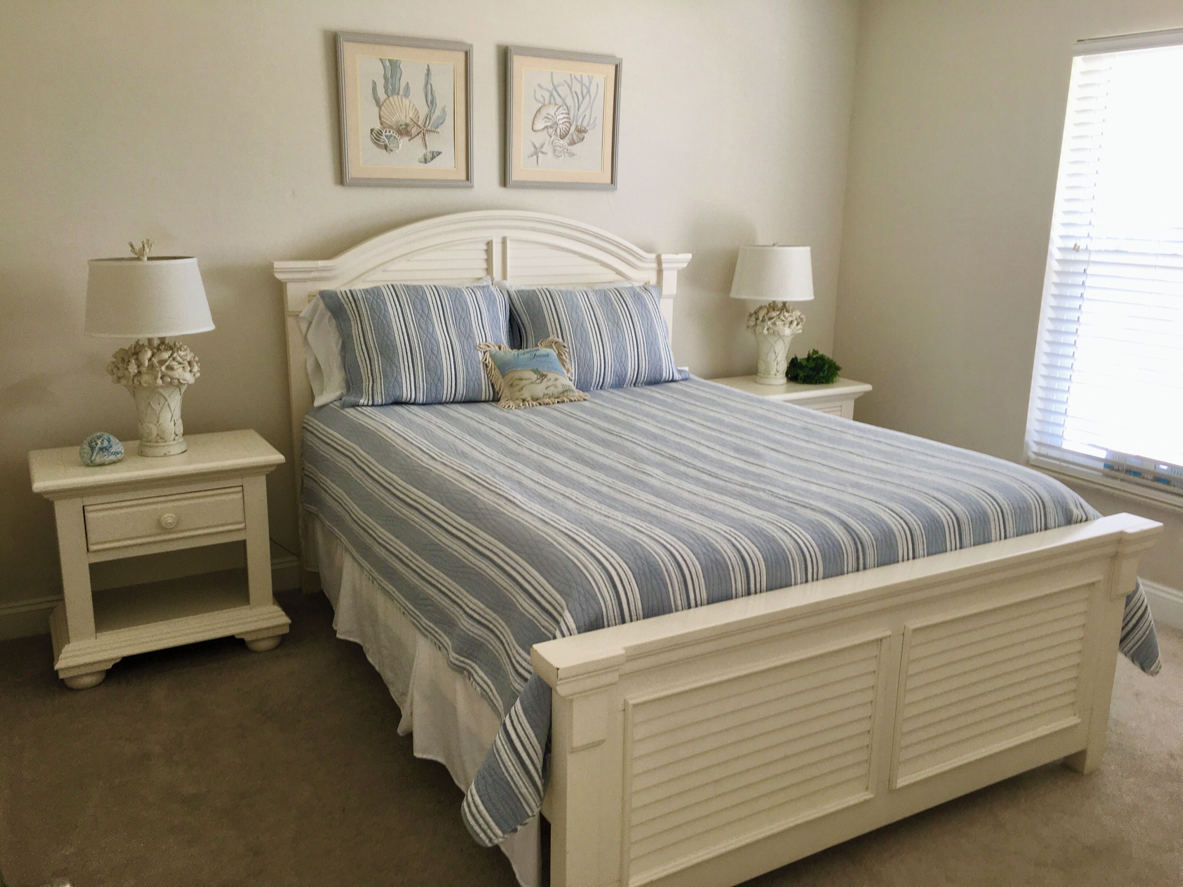 A bedroom with a bed, two nightstands, a dresser, and two framed pictures on the wall.