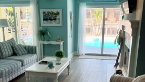 Un salon avec vue sur la piscine, un canapé, une table basse et un téléviseur.