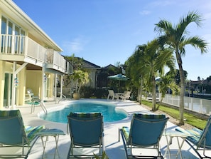 A pool area with lounge chairs and a palm tree.