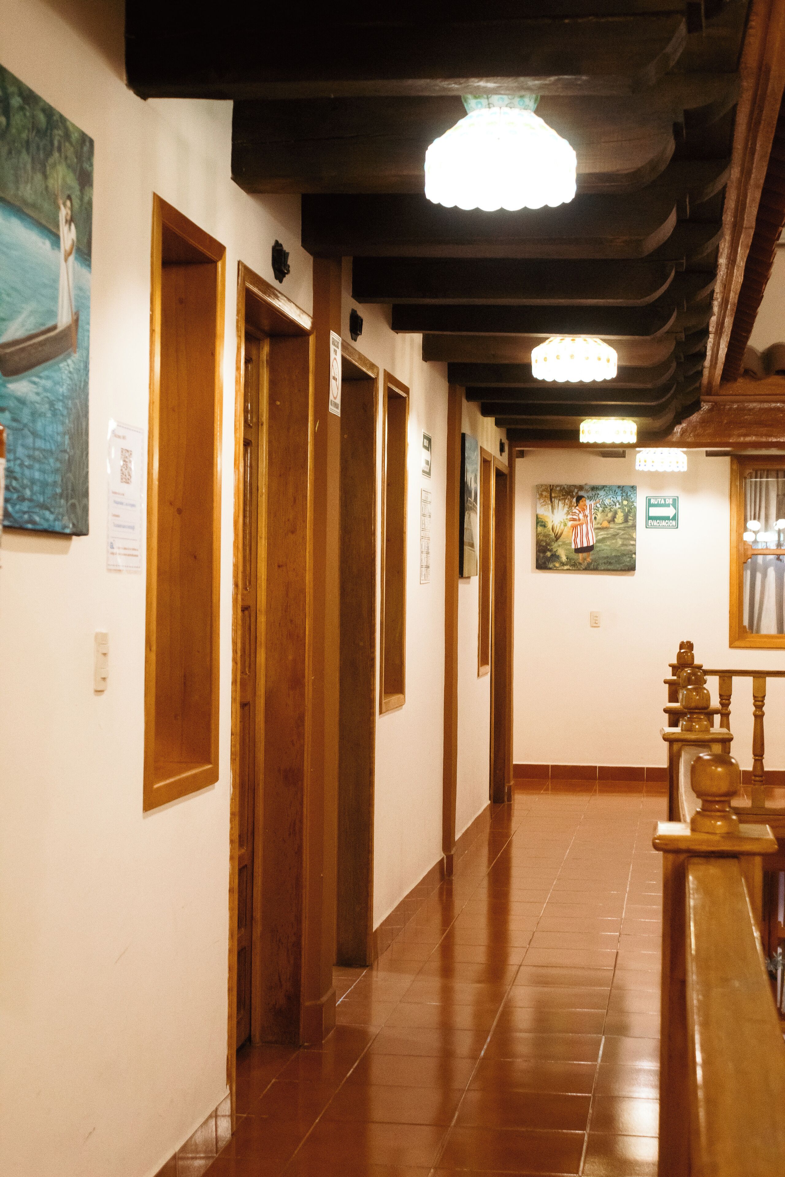 A hallway with wooden doors, tiled flooring, and hanging artwork.