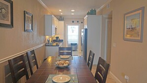 Un coin repas avec une table en bois dressée pour quatre personnes, des chaises et un bol de collations.