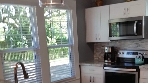 A kitchen with a granite countertop, stainless steel appliances, and white cabinetry.