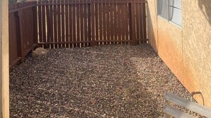 Une terrasse couverte avec vue sur les montagnes, une clôture en bois et un sol en gravier.