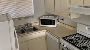 Une cuisine compacte équipée d’un four à micro-ondes, d’une cuisinière, d’un évier et d’un luminaire suspendu.