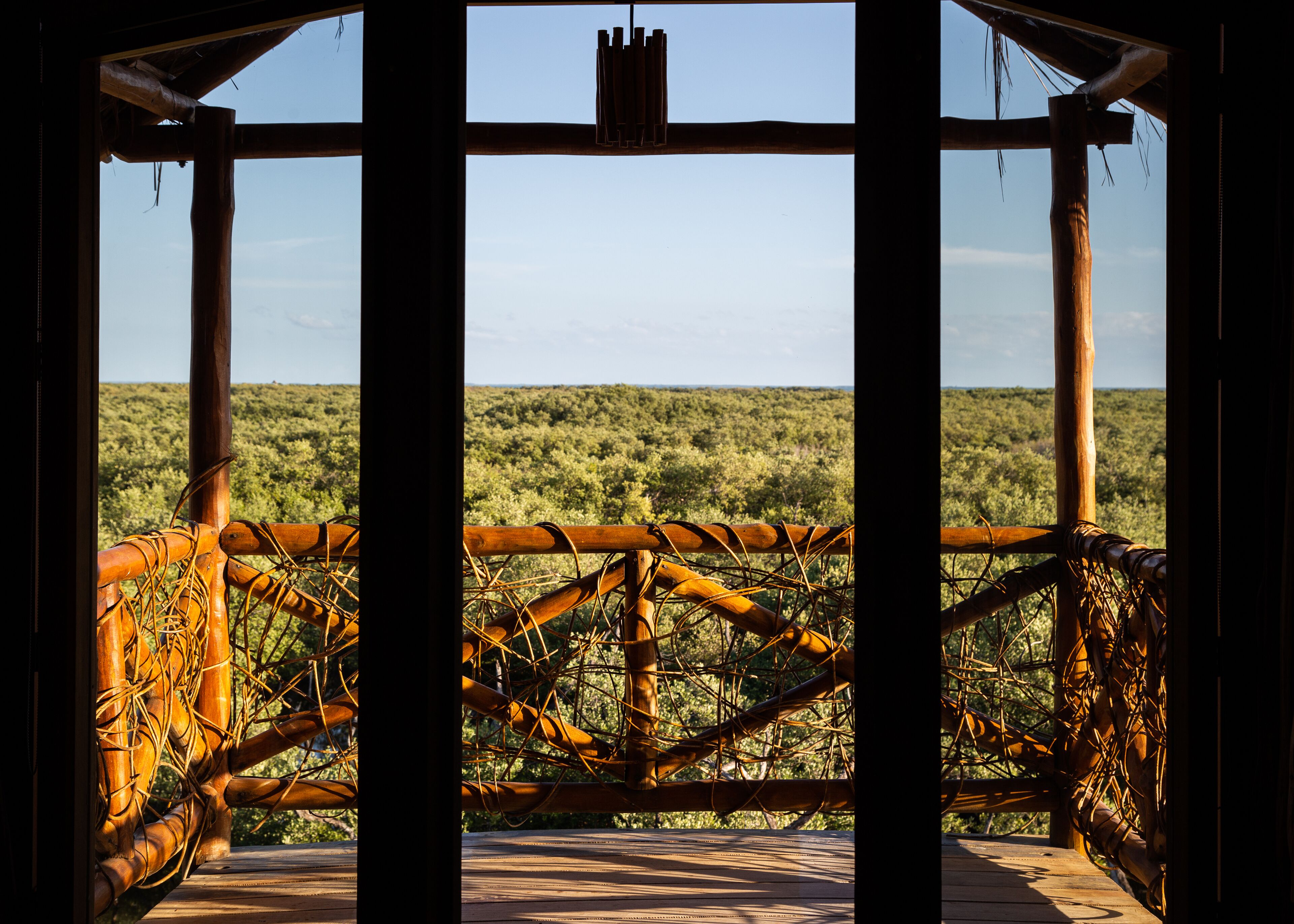 A wooden structure with a view of a dense green landscape.