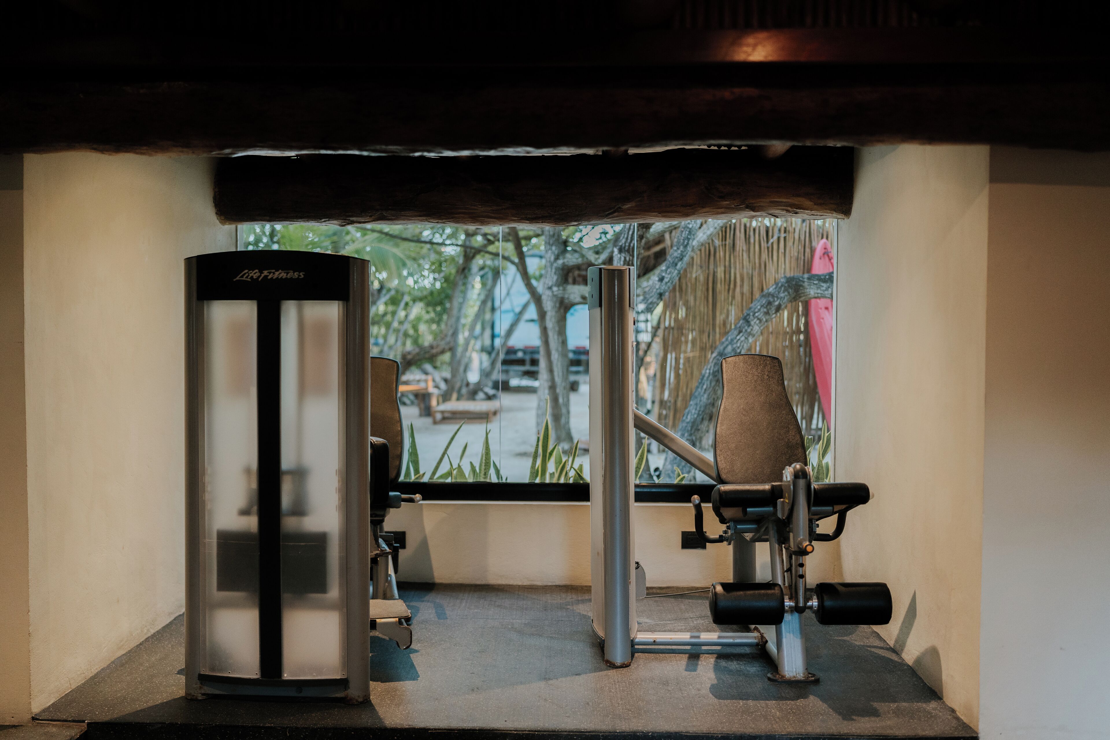 Un gimnasio con equipo de ejercicio, una ventana y vistas al exterior.