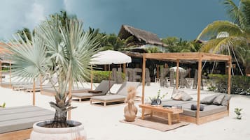 Aan een privéstrand, wit zand, ligstoelen, parasols