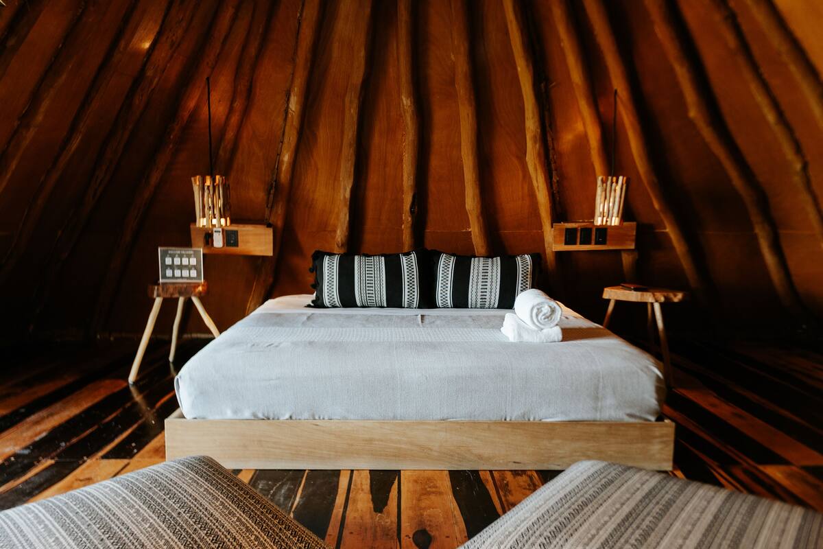 A cozy, wooden-floored bedroom with a bed, pillows, and bedside tables.
