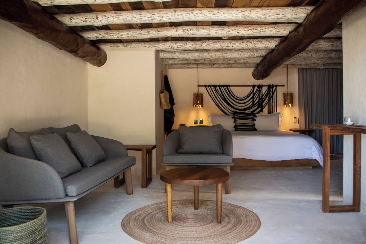 A modern bedroom with a large bed, a sofa, a chair, and a small table.