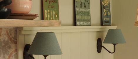 A shelf with decorative signs and two wall-mounted lamps.